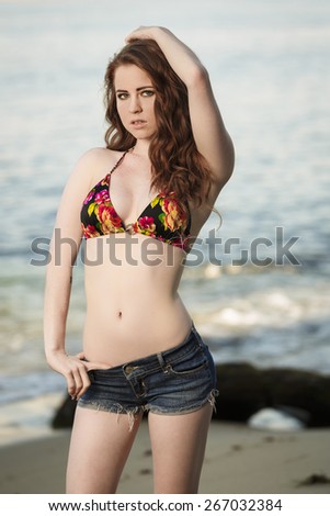 Beautiful young model posing with bikini top and tight jeans shorts