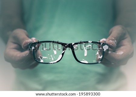 Creative vision concept. Closeup of creative man showing his stained eyeglasses.