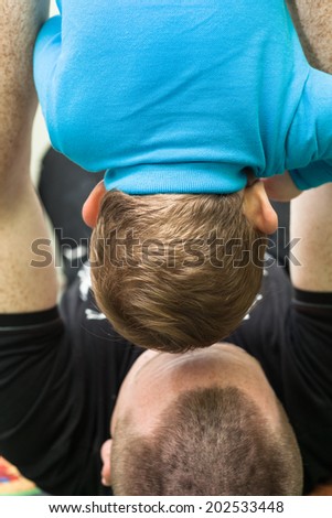 Closeup of daddy holding his son upside down.