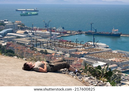 Strait of Gibraltar and middle aged woman tourist resting on the Rock of Gibraltar.
