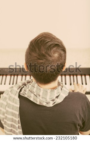 Back view of a man playing piano.