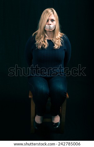 Portrait of scared kidnapped woman hostage with tape over her mouth