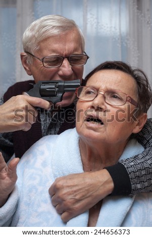 Mad senior couple fighting with a gun.