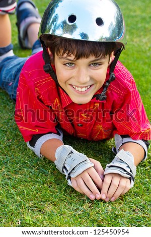 happy boy in roller blades grear laying on grass