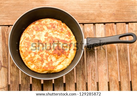 freshly cooked spanish omelette tortilla in pan on wooden table