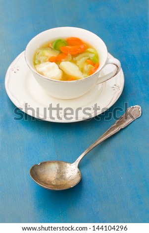 Fish soup with silver spoon on blue wooden table