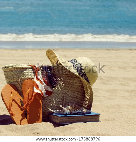 sunbathing accessories on sandy beach by the ocean, toned image