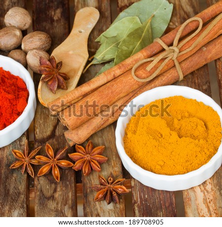 powdered  spices of curry and red pepper with seeds of anise and cinnamon on wooden table
