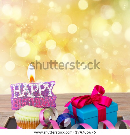 birthday cupcake with burning happy birthday candle on golden background with copy space