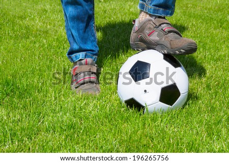 close up of foot and football ball on green grass lawn
