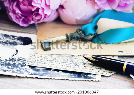 old golden quill pen and antique letters with peonies flowers, shallow focus on pen feather