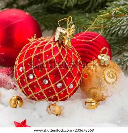 red  and gold christmas ball in snow under fir tree