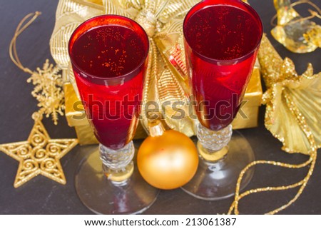 two red glasses with christmas champagne and golden decorations