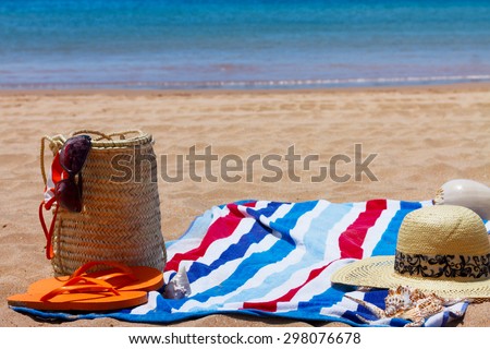 sunbathing accessories on sandy beach in straw bag at sunny day