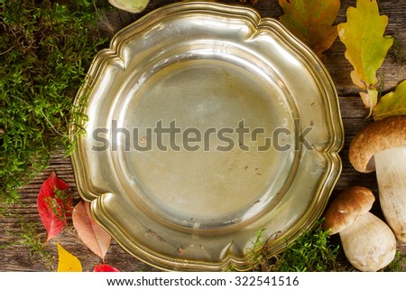 Empty tin plate with frame of boletus mushrooms on wooden table