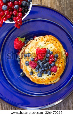Pancakes with   berries on blue plate, top view