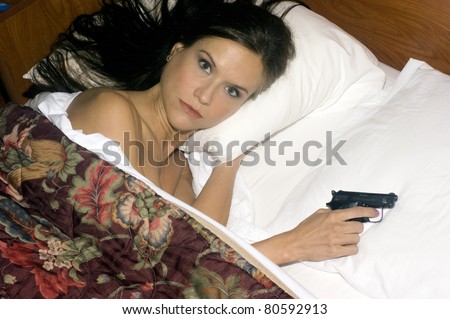 Woman Looking up Surprised in bed hand under pillow on Gun Self Defense Weapon
