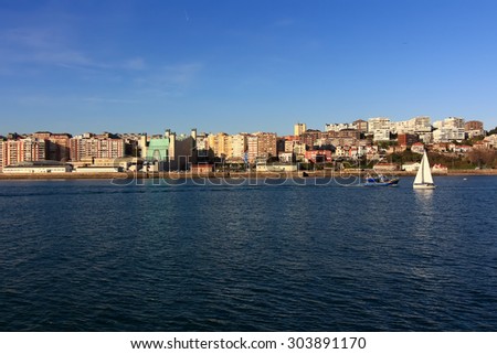 small sailboat white sailing in front of the city of Santander, Spain