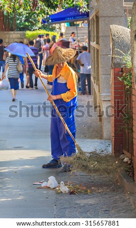 September 14, 2013 -Gulangyu, China: Street sweeper sweeps a busy shopping street in center of the island