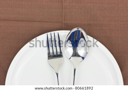 Spoon and fork on a dish as a dining room serving.