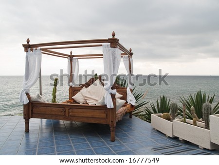 Four poster bed on patio by the sea