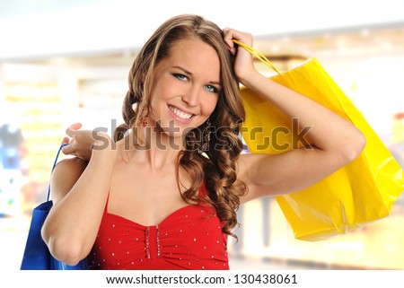 Young and beautiful woman with shopping bags smiling inside a mall