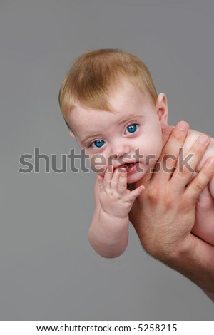 baby being held in Dad\'s hand isolated on gray