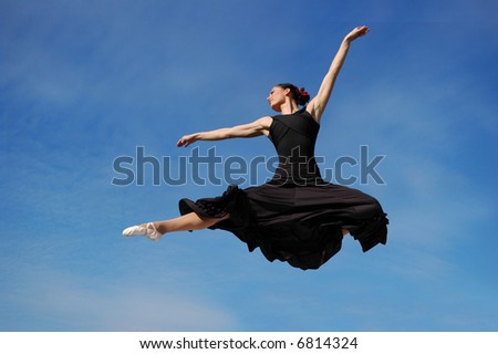 Dancer jumping against blue sky wearing black