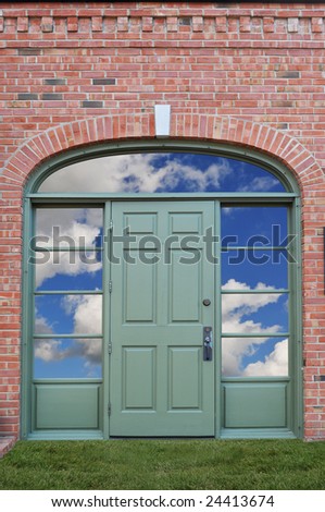Green door with clouds behind and grass as a carpet