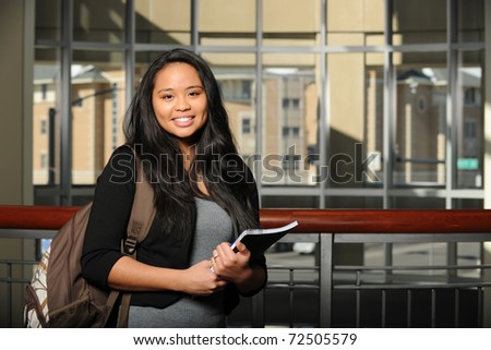 Young Oriental Woman Student holding a copybook inside a college campus