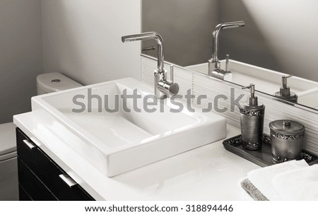 Bathroom detail in new luxury home: sink and faucet with partial view of toilet