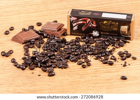 Seoul, South Korea - April 8, 2015: A box of Handy Cafe, Dark Roast edition, liquid coffee-filled chocolate candy by Lotte Co., Ltd. is displayed with pieces of chocolate candy and coffee beans.