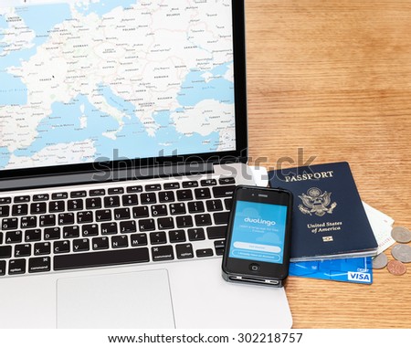 Seoul, South Korea - July 29, 2015; An illustrative editorial of travel planning using a map app on a laptop, the Duolingo language learning app on an iPhone, passport, and Visa Debit card.