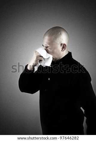 A man sneezing into a tissue