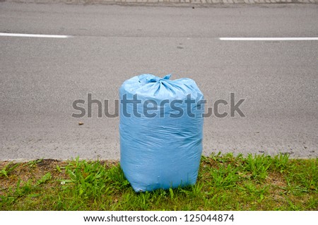 blue garbage plastic bag on city street