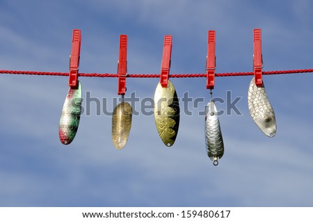 Various vintage metal lures - spoons on cloth string and sky background. Fishing concept