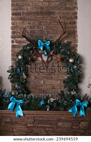 Christmas wreath of holly with blue bows over the fireplace, a cozy winter evening