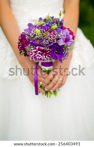 Beautiful white and purple bridal bouquet in her hands