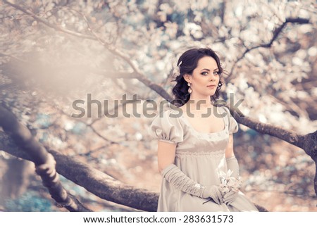 Beautiful girl in vintage satin dress in the lush spring garden magnolia