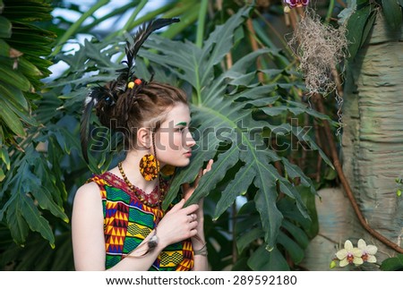 Beautiful young girl in colored clothes on a bright background of tropical nature, summer heat