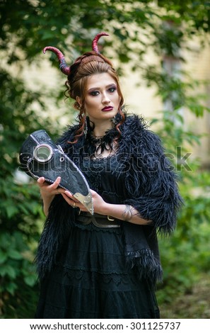 Beautiful young woman ominous, witch in a black dress with a plague doctor mask in the style of steam-punk