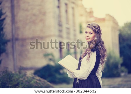 The girl in black vintage dress reading a book in the courtyard of the old university