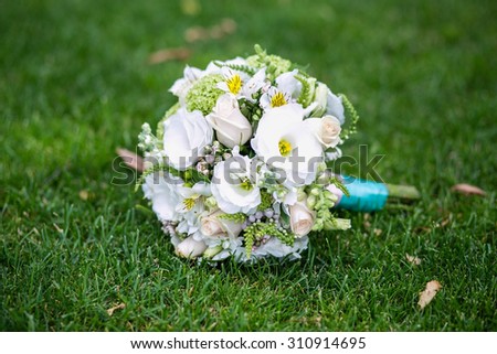 Beautiful round wedding bouquet of bribe lies on the lawn