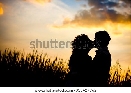 A loving couple, man and woman, black silhouettes against the bright sunset date on nature