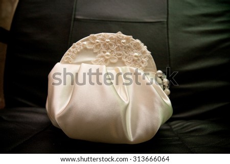 Elegant handbag bride in a white satin clutch, embroidered with pearls