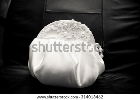 Elegant handbag bride in a white satin clutch, embroidered with pearls, black and white photo