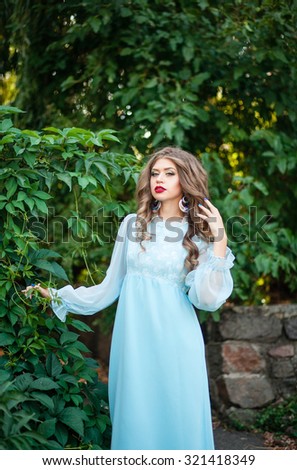 Beautiful girl in a long dress the color of mint walk on summer garden