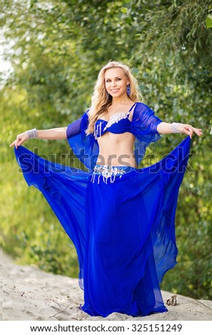 Dancer belly dance in a bright blue dress is ready to fulfill the Arab national oriental dance