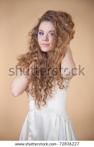 Beautiful girl on a beige background with nice lush hair.