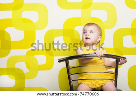 Little girl sits on a bar stool with a bright yellow dress.
